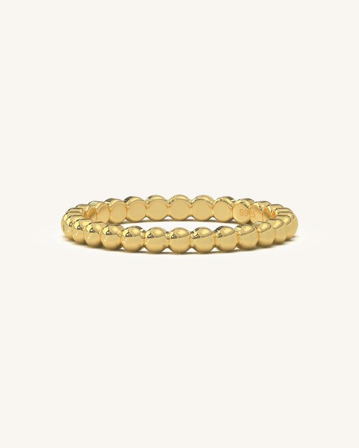 Close-up of a beaded gold vermeil ring on a white background, showcasing its intricate texture and shine.