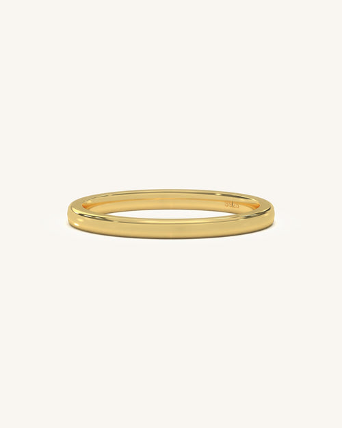 A simple, polished plain gold vermeil sterling silver ring on a neutral background, highlighting its smooth finish.