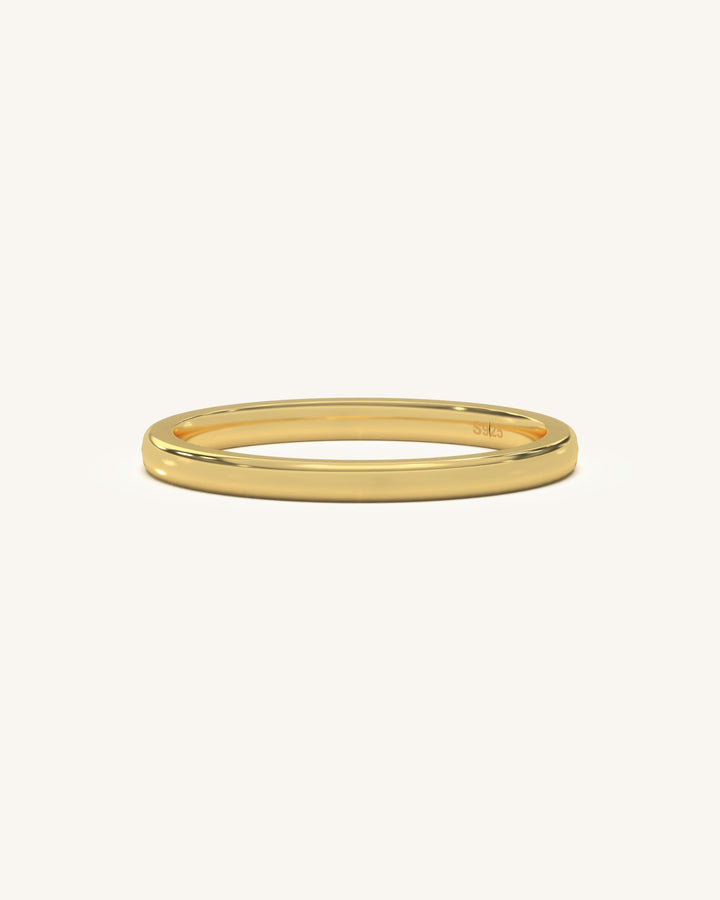 A simple, polished plain gold vermeil sterling silver ring on a neutral background, highlighting its smooth finish.