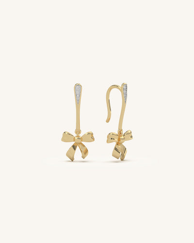 Modern two-tone bow earrings featuring a matte gold bow suspended from a diamond-studded white bar, in 18KT gold vermeil.