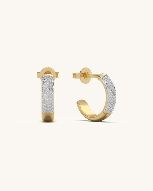 Close-up of Tiny Hoop Earrings in 18KT Gold Vermeil with moissanite diamonds, showcasing their sleek half-hoop design and modern cylindrical shape on an earlobe.