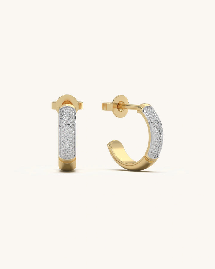 Close-up of Tiny Hoop Earrings in 18KT Gold Vermeil with moissanite diamonds, showcasing their sleek half-hoop design and modern cylindrical shape on an earlobe.