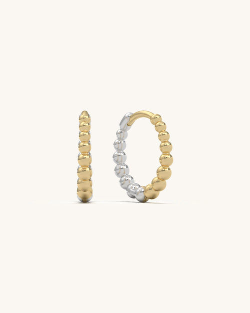 Pair of gold vermeil beaded loop huggie earrings on a light background, showcasing intricate beadwork and shine.