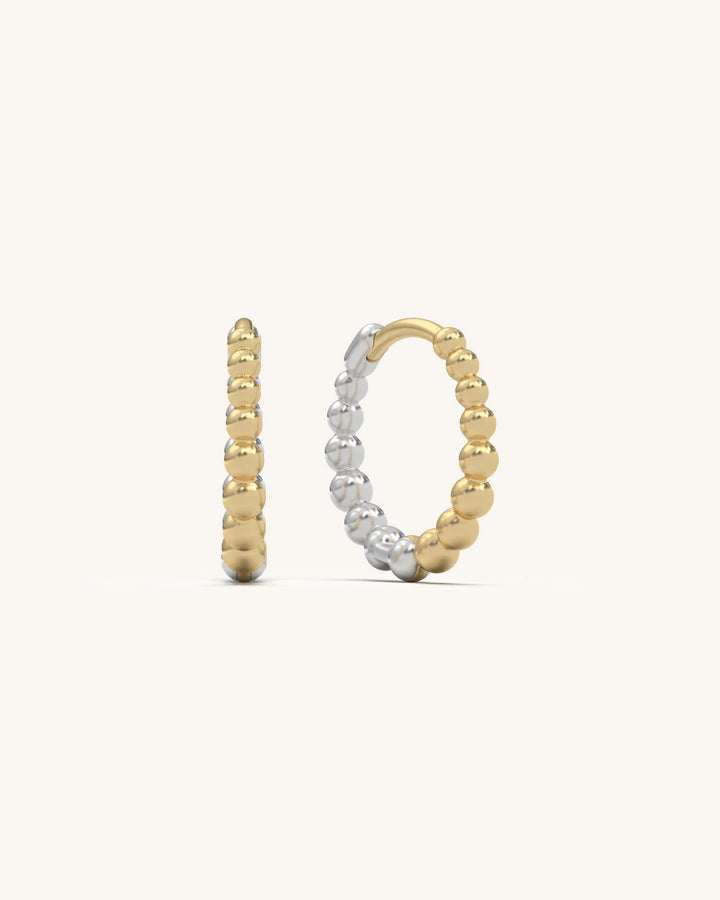Pair of gold vermeil beaded loop huggie earrings on a light background, showcasing intricate beadwork and shine.